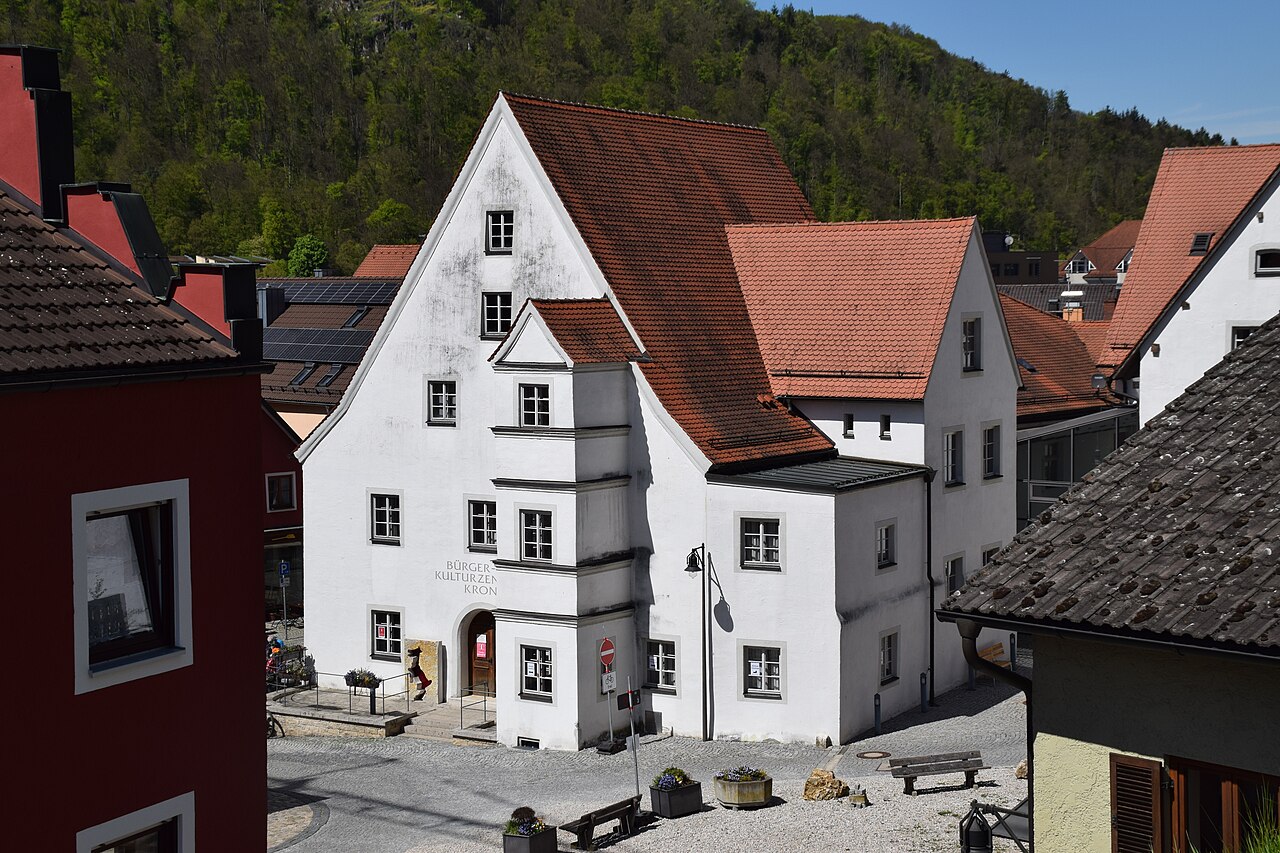zweigeschossiger Steilgiebelbau mit dreigeschossigem Steherker, nördlich in gleicher Traufhöhe anschließend ehem
