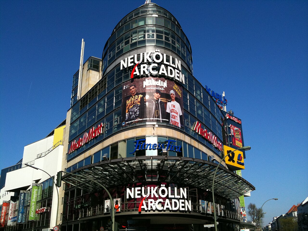 Movie poster of "Neukölln Unlimited" hanging from the facade of a shopping centre in Berlin-Neukölln