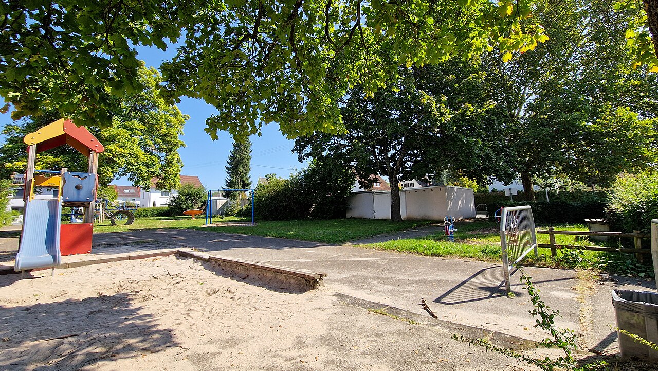 Von einem bunten Spielturm führt eine hellblaue Plastikrutsche in einen großen Sandkasten