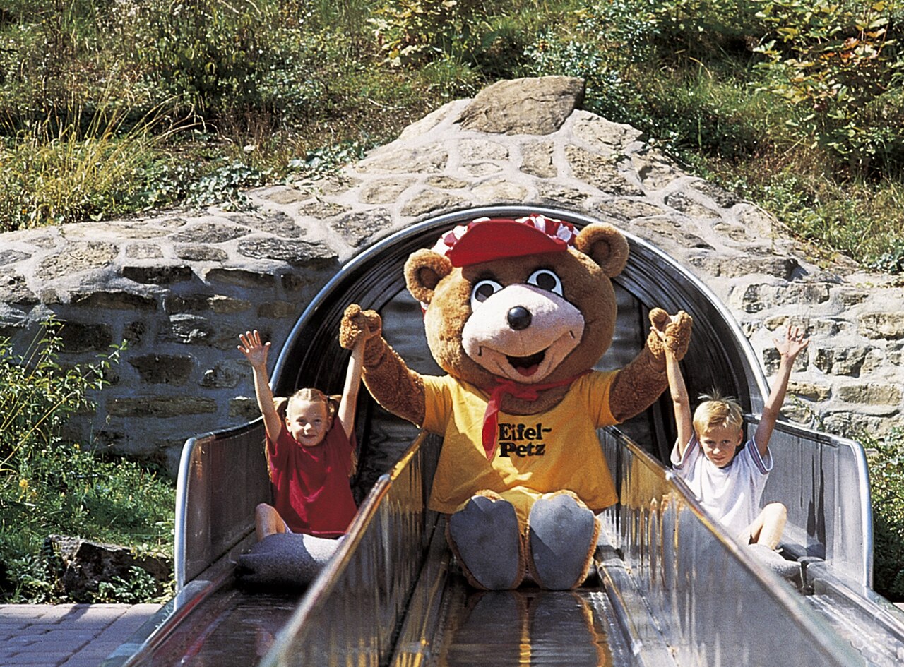 ifelpetz (Maskottchen Eifelpark) mit Besuchern auf der Freifallrutsche