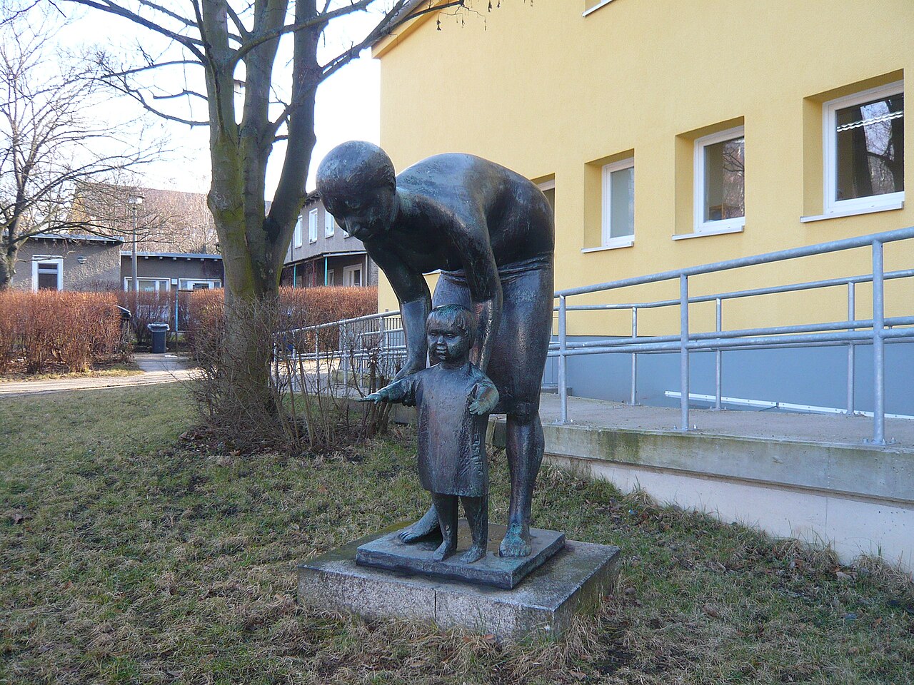 Berlin-Prenzlauer Berg, Pieskower Weg 49/50: Kita Sonnenschein, Bronzeskulptur Frau mit Kleinkind davor