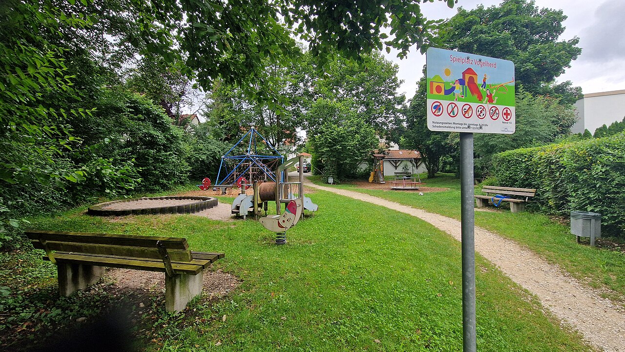 Der Spielplatz Vogelherd ist von grünen Hecken und hohen Bäumen umfriedet